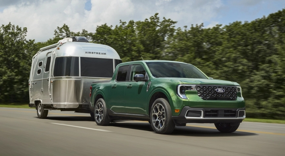 A green 2026 Ford Maverick towing an Airstream Camper